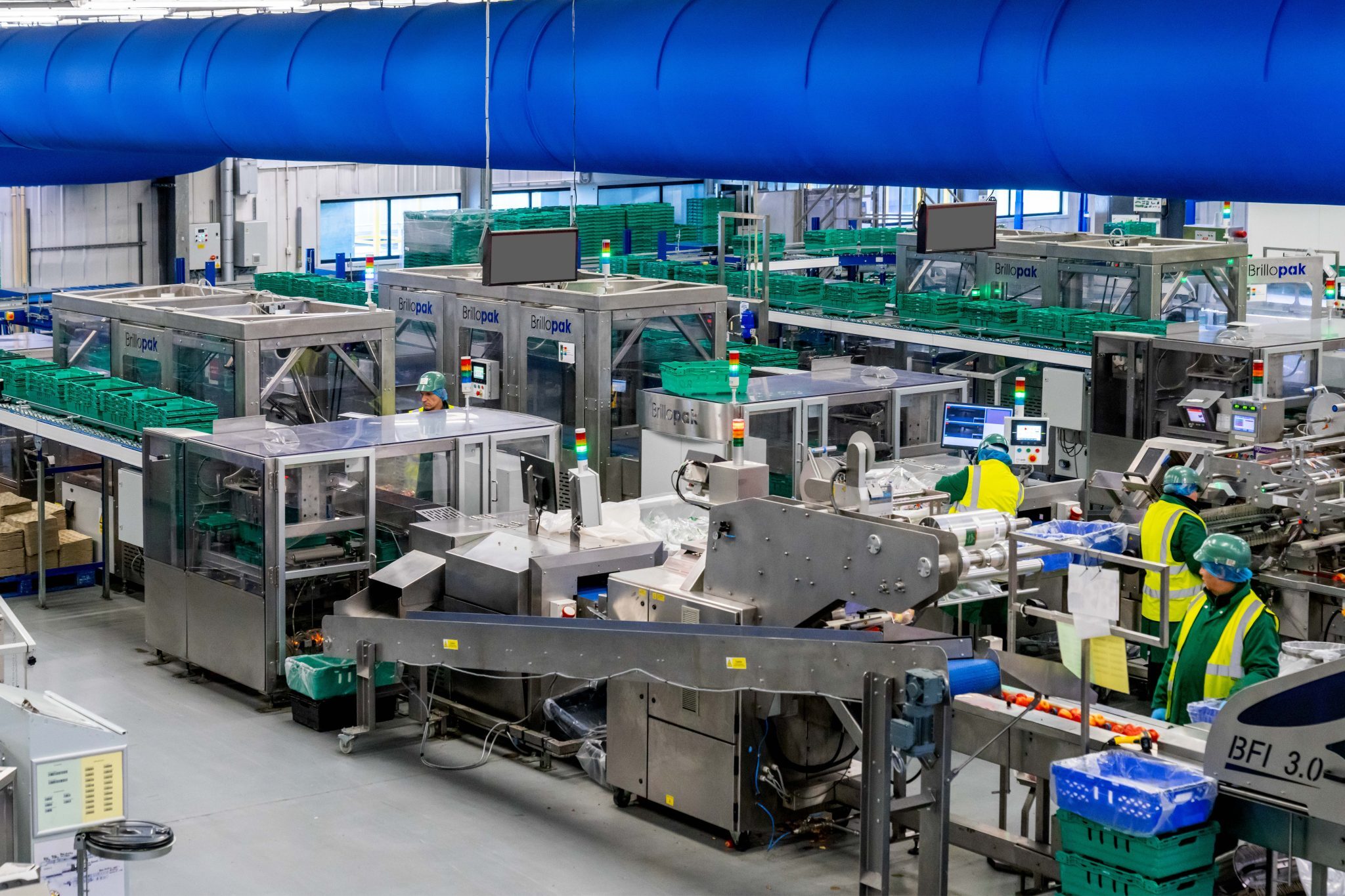 Crates and packaged food are produced on a rolling conveyor during end-of-line packaging automation.