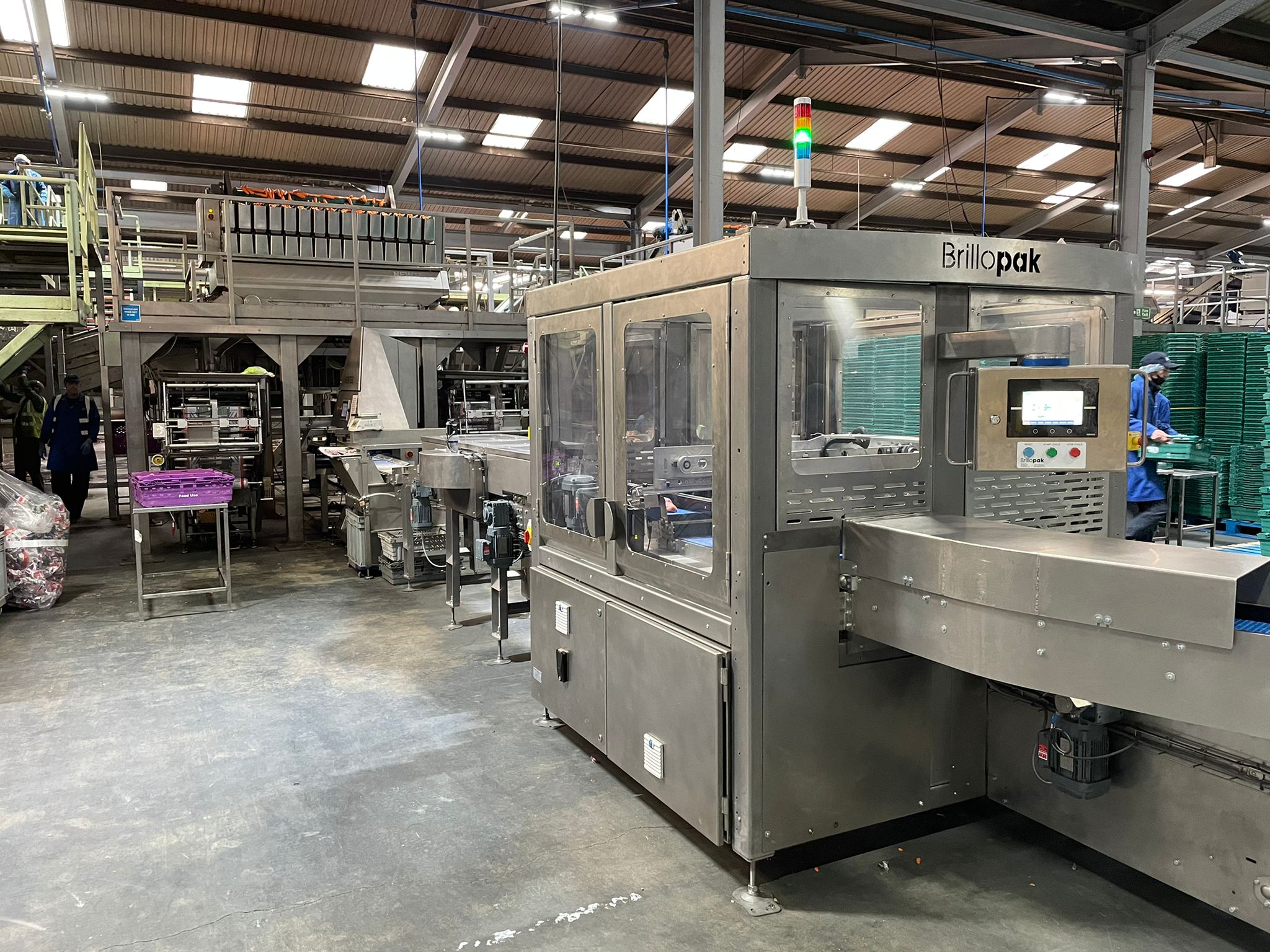 An automated packing machine by Brillopak operating in a warehouse setting, illustrating the high-tech environment and potential complexities that end-users may face in adopting automation solutions, including system integration and operational efficiency challenges.