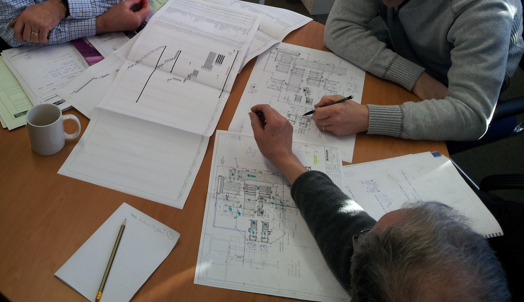 The team at Brillopak discussing complex engineering details and reviewing technical drawings, symbolising the precision and collaborative planning needed to navigate the complexities of packing automation for bespoke products.